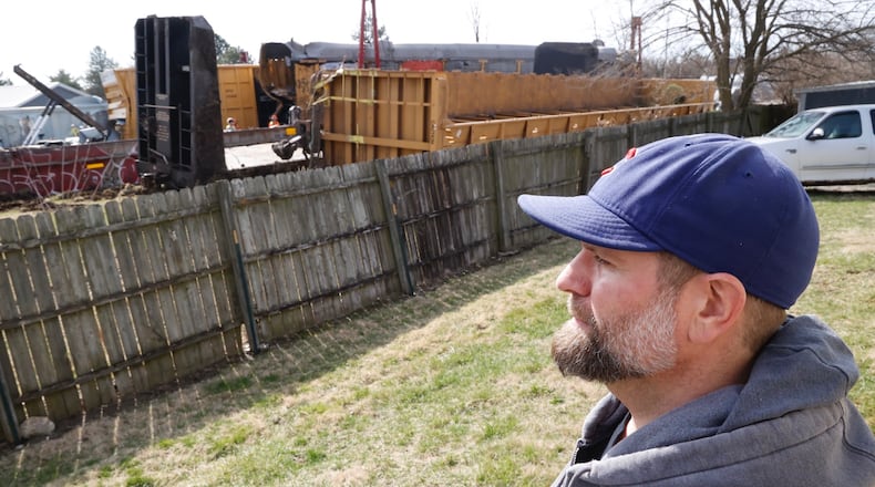 Lane Martin, the owner of Ability Builders, watches the cleanup of the train derailment on the other side of his fence Monday, March 6, 2023. Lane said he feels lucky that Saturday’s derailment stopped just before his Springfield Twp. business. BILL LACKEY/STAFF