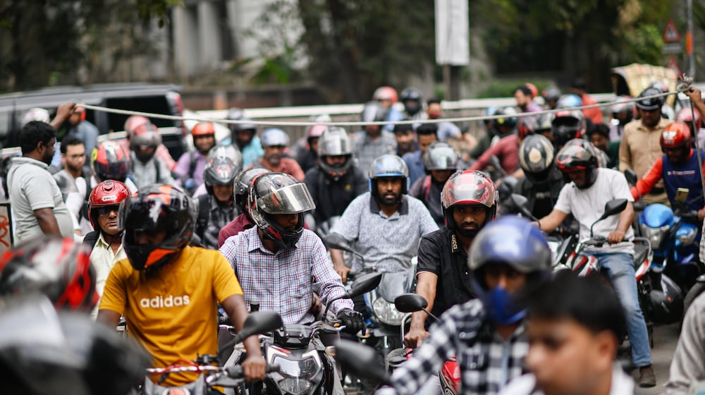 Motorists queue up as others wait behind a rope for their turn to get fuel at a pump, fearing a possible fuel shortage due to the Iran war, in Dhaka, Bangladesh, Sunday, March 8, 2026. (AP Photo/Mahmud Hossain Opu)