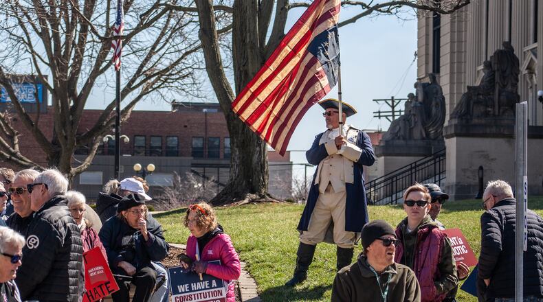 A demonstrator wearing a Revolutionary War uniform holds an upside-down Betsy Ross U.S. flag during a "No Kings" protest outside the Illinois State Capitol in Springfield, Ill., on Saturday, March 28, 2026. (Jenna Schweikert, Capitol News Illinois via AP)