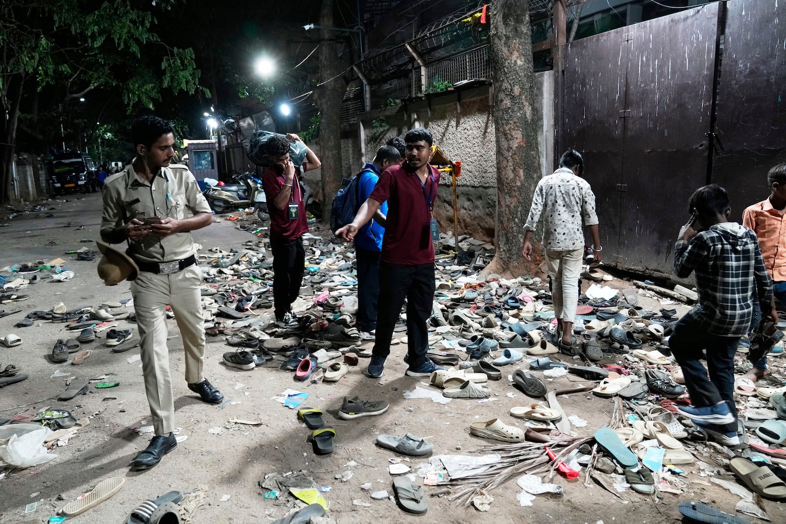 People rummage through footwear strewn outside M. Chinnaswamy Stadium after a stampede caused by frenzied fans celebrating Royal Challengers Bengaluru's victory in the Indian Premier League cricket tournament, in Bengaluru, India, Wednesday, June 4, 2025. (AP Photo/Aijaz Rahi)