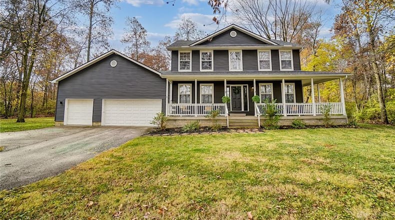 The front of the home features a wraparound porch with railing and a three-car attached garage. Contributed photo