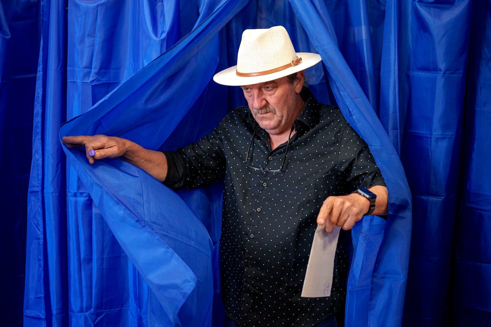 A man exits a voting booth before casting his vote in the first round of the presidential election redo in Bucharest, Romania, Sunday, May 4, 2025. (AP Photo/Andreea Alexandru)