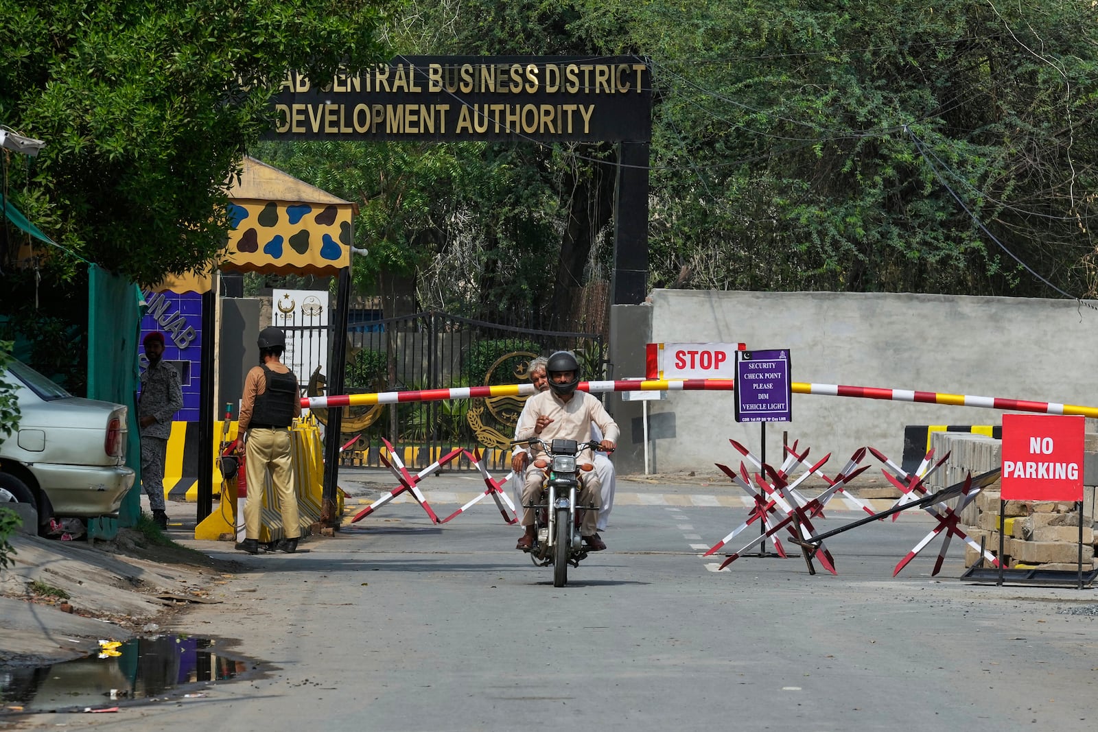 A motorcyclist drive through a checkpoint on an entry point to a garrison area, where a suspected Indian drone crashed, in Lahore, Pakistan, Thursday, May 8, 2025. (AP Photo/K.M. Chaudary)