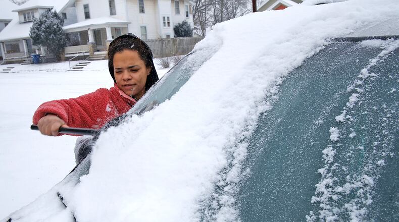 Brittany McNeal uses a broom to clean the snow off her car Friday, Jan. 19, 2024 along Cedar Street in Springfield. BILL LACKEY/STAFF