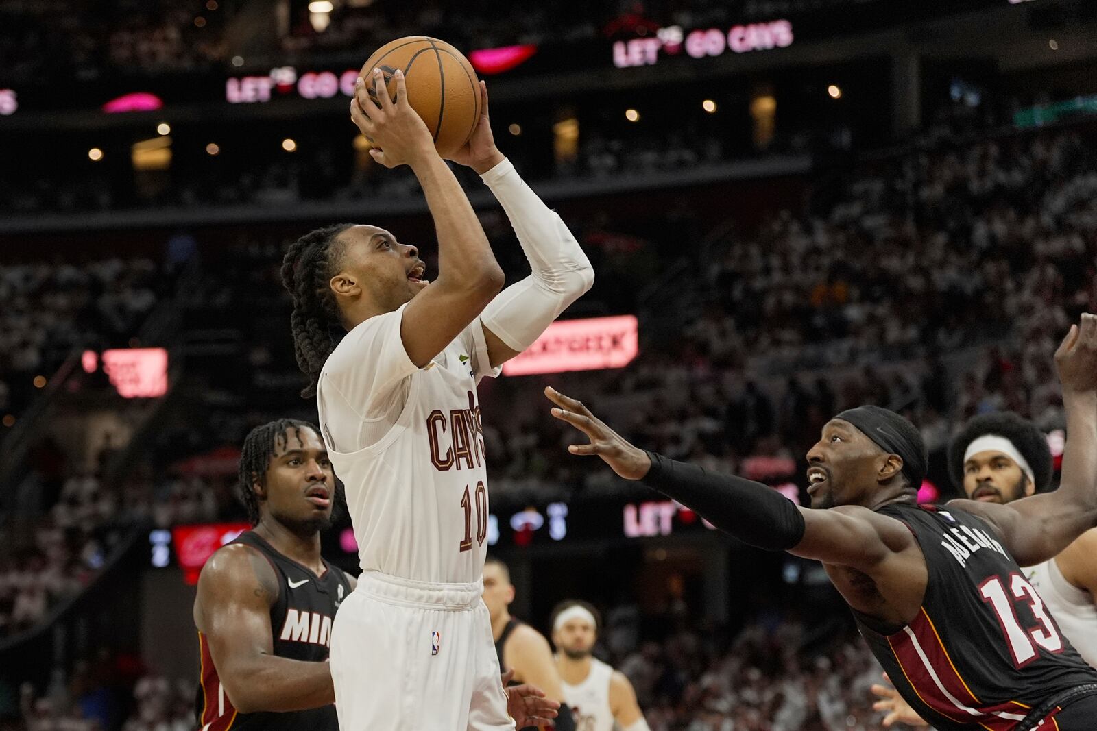 Cleveland Cavaliers guard Darius Garland, center, goes to the basket between Miami Heat guard Davion Mitchell, left, and center Bam Adebayo (13) in the second half in Game 2 of an NBA first-round playoff series, Wednesday, April 23, 2025, in Cleveland. (AP Photo/Sue Ogrocki)