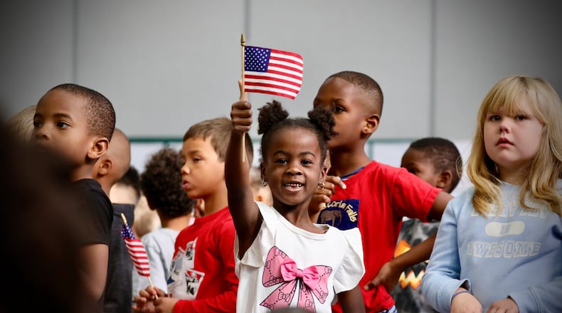 A student at Kenwood Elementary School waves an American flag during a Veterans Day ceremony at the school on Nov. 11, 2025. Hundreds of students in the Springfield City School District came together to honor veterans through a ceremony with special veteran guests and performances and coloring patriotic pictures to be delivered to local restaurants for veterans. Contributed