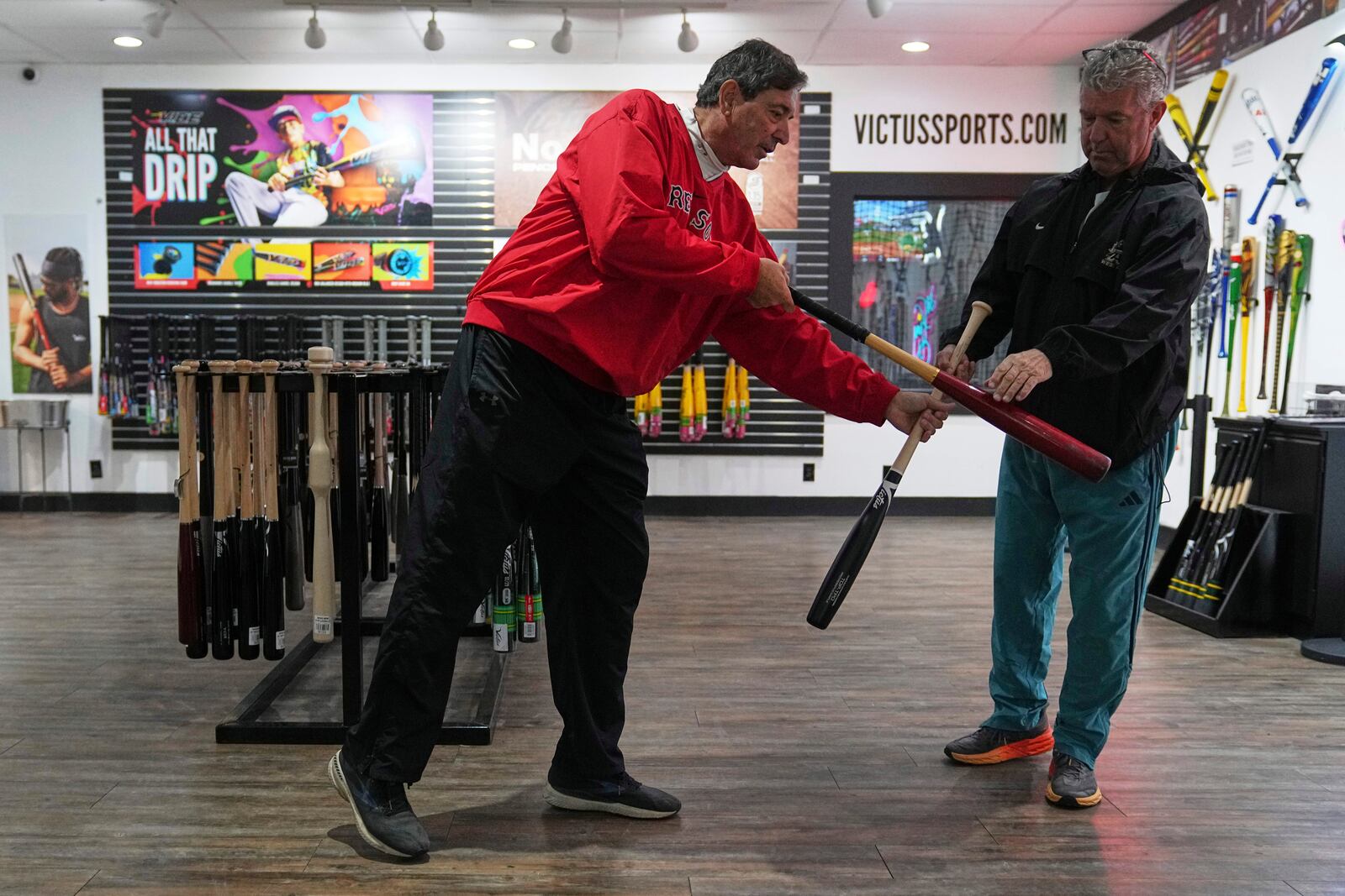 Customers Ed Costantini, left, and Jack Bradley compare a conventional bat with a torpedo baseball bat at Victus Sports in King of Prussia, Pa., Wednesday, April 2, 2025. (AP Photo/Matt Rourke)