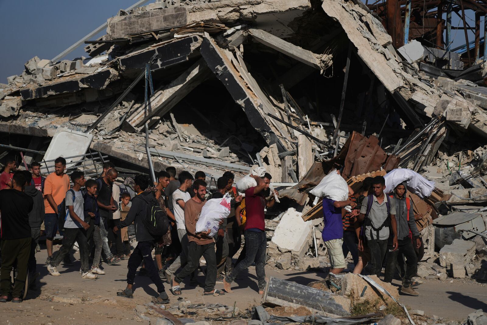 Palestinians carry humanitarian aid packages distributed by the Gaza Humanitarian Foundation operated by the U.S.-backed organization in Khan Younis, southern Gaza Strip, Thursday, June 26, 2025. (AP Photo/Abdel Kareem Hana)