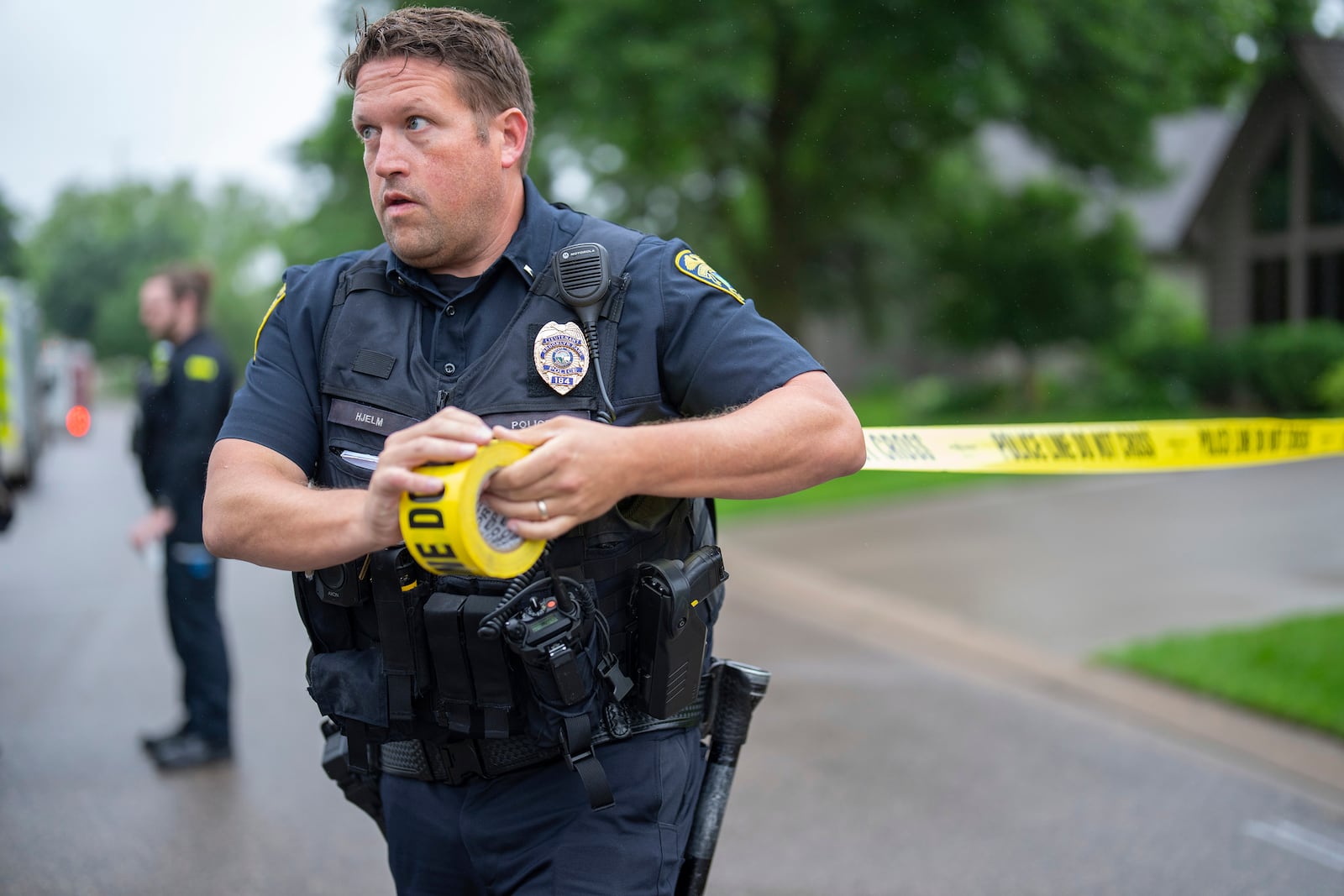 Brooklyn Park Police Lieutenant Hjelm sets up a perimeter with police tape near the scene of a shooting in Brooklyn Park, Minn. on Saturday, June 14, 2025. (Alex Kormann/Star Tribune via AP)
