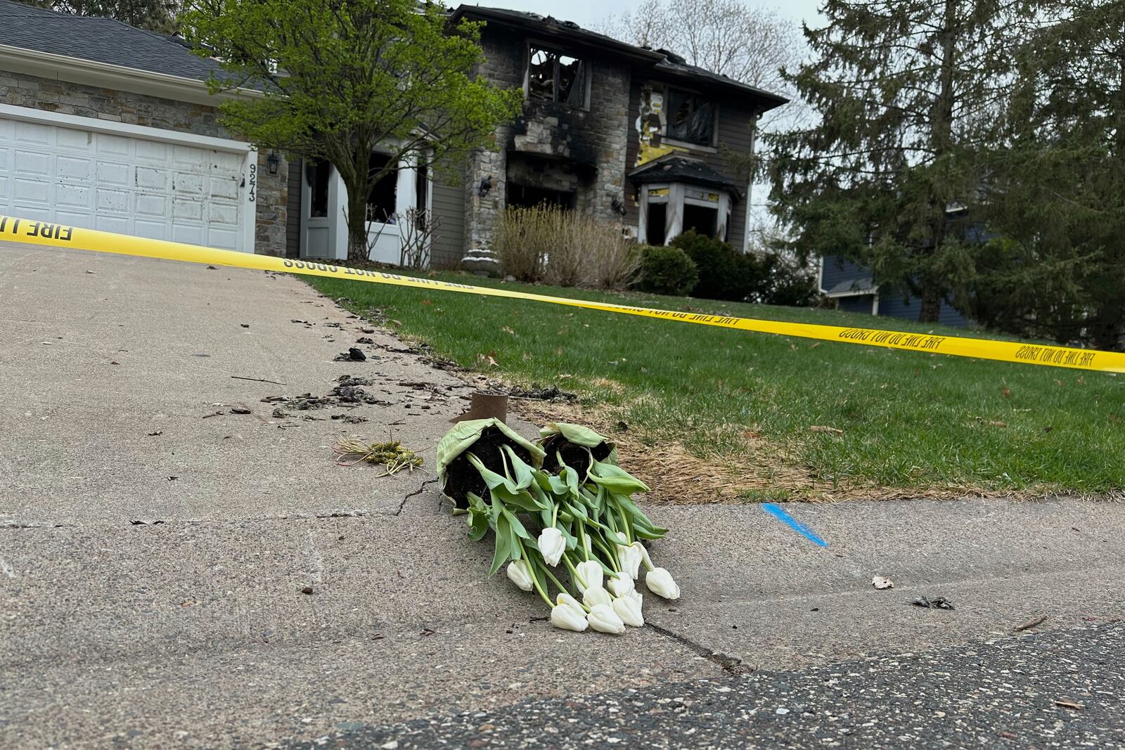 Flowers are left in the driveway at the home of Jill Sobule on Friday, May 2, 2025, in Woodbury, Minn., a day after a fire engulfed the house, killing the 66-year-old singer-songwriter. (AP Photo/Amy Forliti)