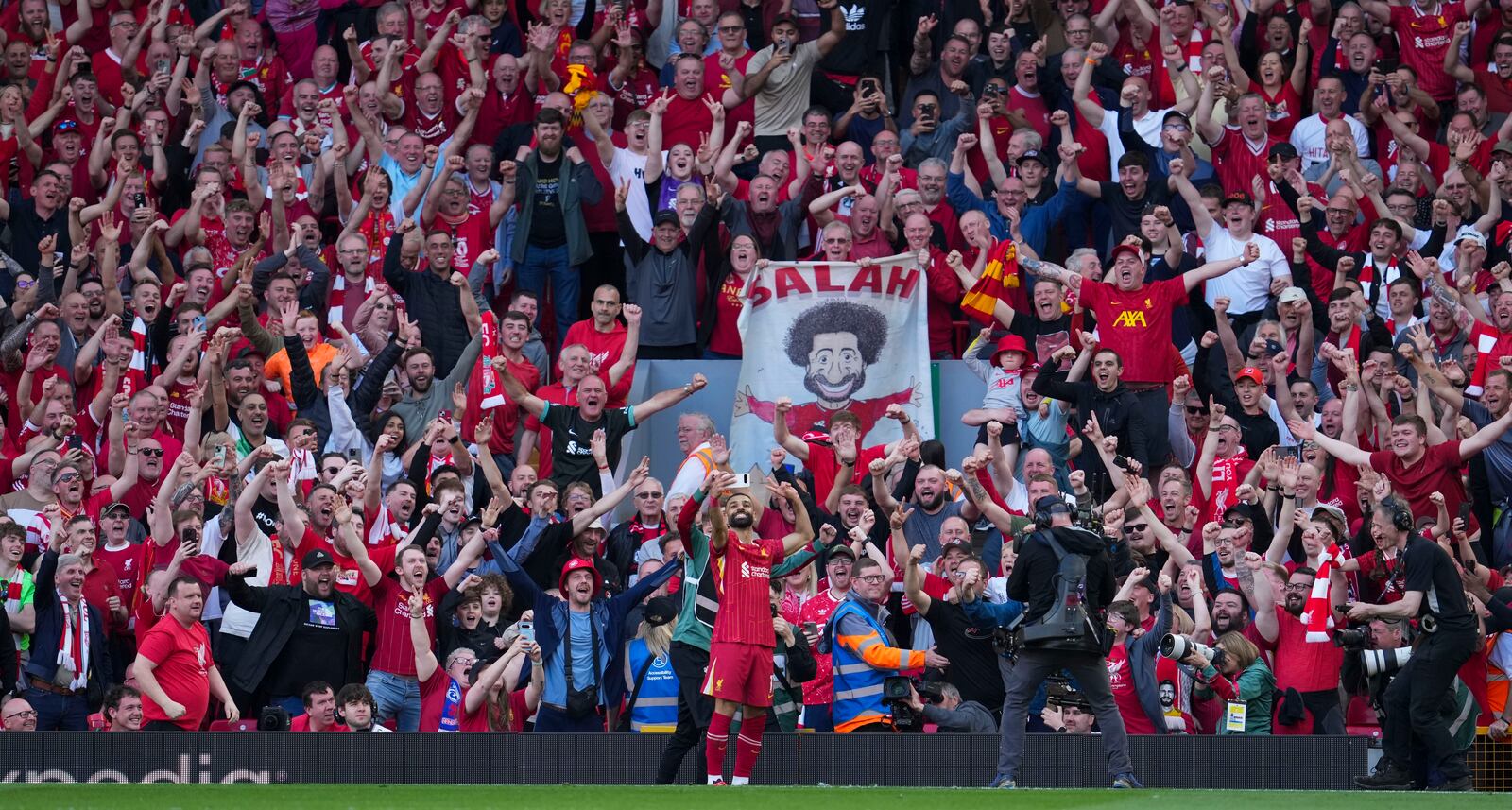 Liverpool's Mohamed Salah takes a selfie with a fans smartphone as he celebrates after scoring his side's fourth goal during the English Premier League soccer match between Liverpool and Tottenham Hotspur at Anfield in Liverpool, England, Sunday, April 27, 2025. (AP Photo/Jon Super)