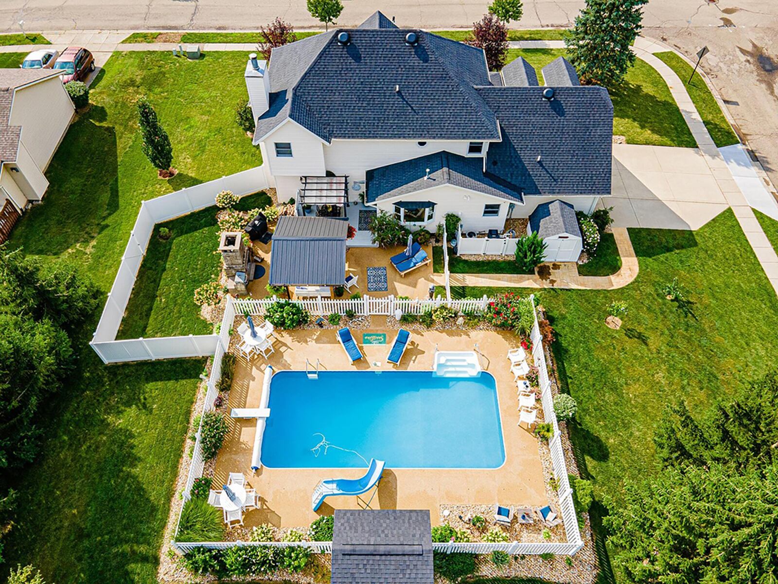 The home’s back features a heated, inground pool surrounded by vinyl privacy fence, a pool house, a deck with covered pergola, extended Nature Stone patio, outdoor fireplace with oven and firewood storage and grassy area with mature trees. CONTRIBUTED PHOTO