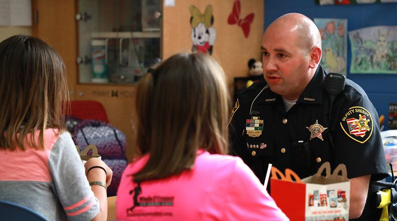 Deputy John Loney, the school resource officer for the Tecumseh School Destrict, provides a caring ear along with lunch for two students going through a stressful time at home. FILE PHOTO. BILL LACKEY/STAFF