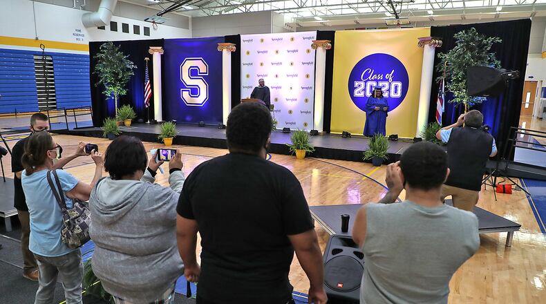 Clark and Champaign County schools will host their 2021 graduation ceremonies outside. Here, a family takes pictures of their Springfield High School graduate as she receives her diploma in an individual ceremony in 2020. BILL LACKEY/STAFF