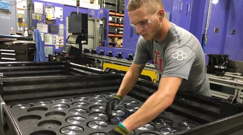 Michael Lensman arranges gears after cutting them on a Crown Equipment assembly line in New Bremen. THOMAS GNAU/STAFF