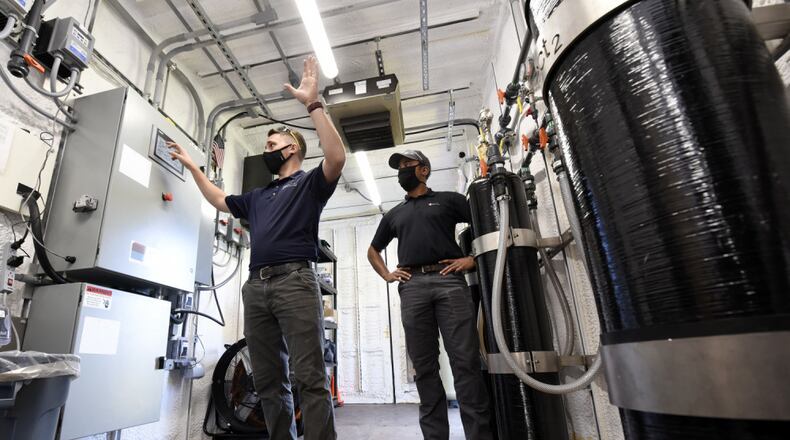 Dan Casey, left, lead field operations engineer, and Brad Geisman, pilot engineer for Emerging Compounds Treatment Technologies (ECT2), discuss a water filtration system being used to remediate PFAS from contaminated groundwater at the fire training area of Wright-Patterson Air Force Base on Sept. 29, 2020. U.S. Air Force personnel from the 88th Air Base Wing Civil Engineer Group are leading the pilot study of new remediation techniques that can remove and destroy the PFAS, some of which were formerly used in aircraft fire fighting foam./CONTRIBUTED