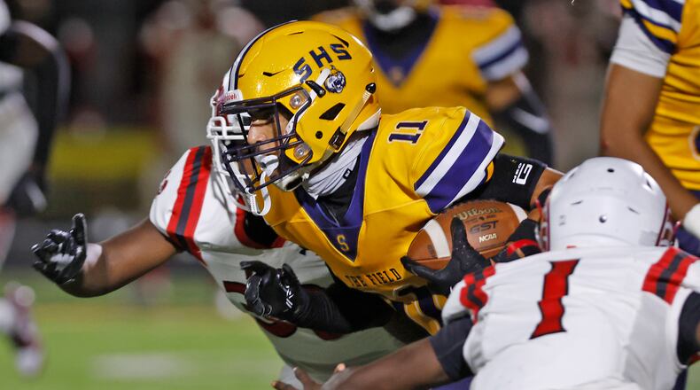 Springfield's Jamil Miller breaks through the Trotwood defensive line as he carries the ball. BILL LACKEY/STAFF
