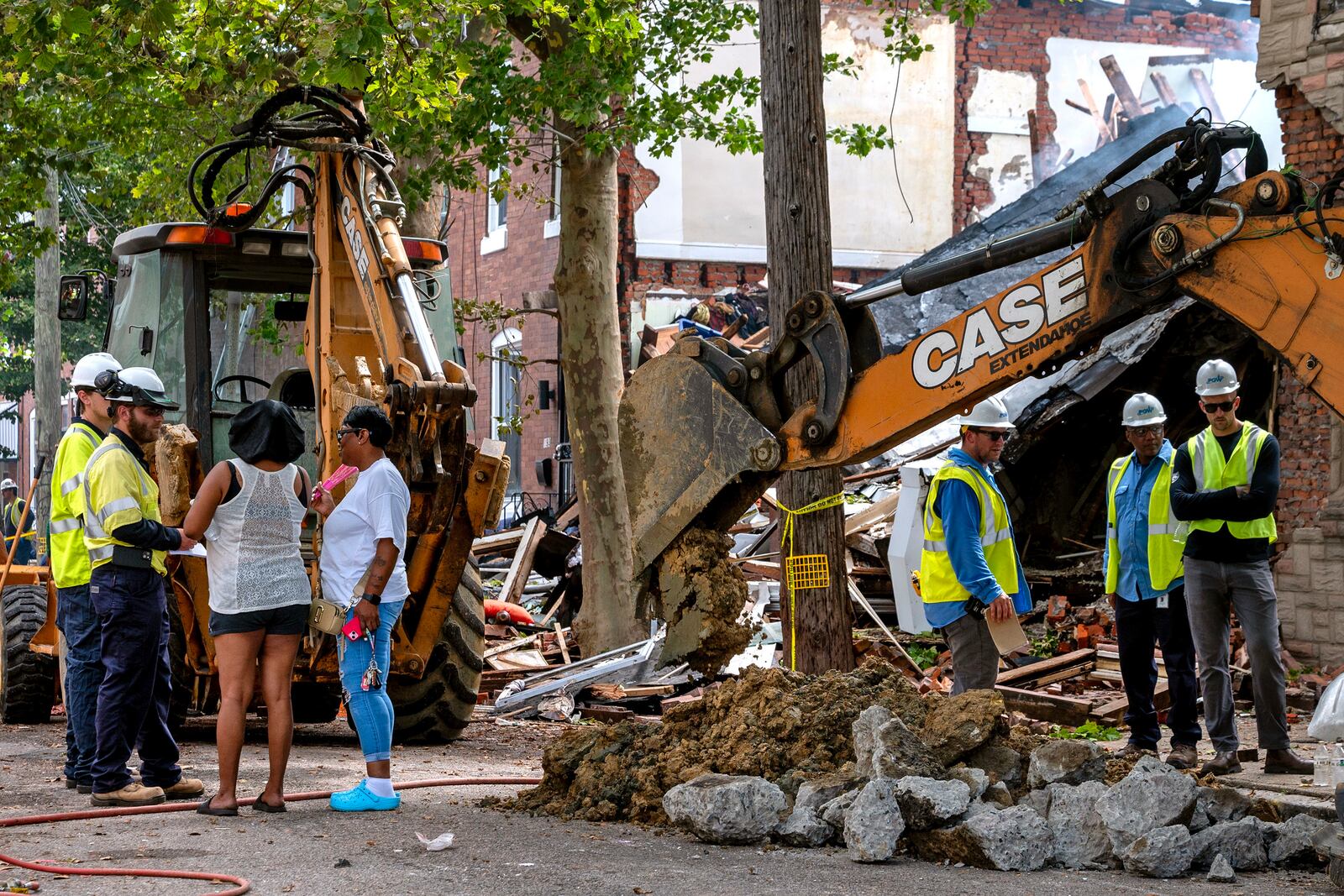 Tamara Davis, left, with her aunt, Karen Leake, right, talk with inspectors outside her home in the Nicetown area of Philadelphia, Sunday, Jun. 29, 2025, where there were fatalities after three row houses collapsed after a fire and explosion. (Tom Gralish/The Philadelphia Inquirer via AP)