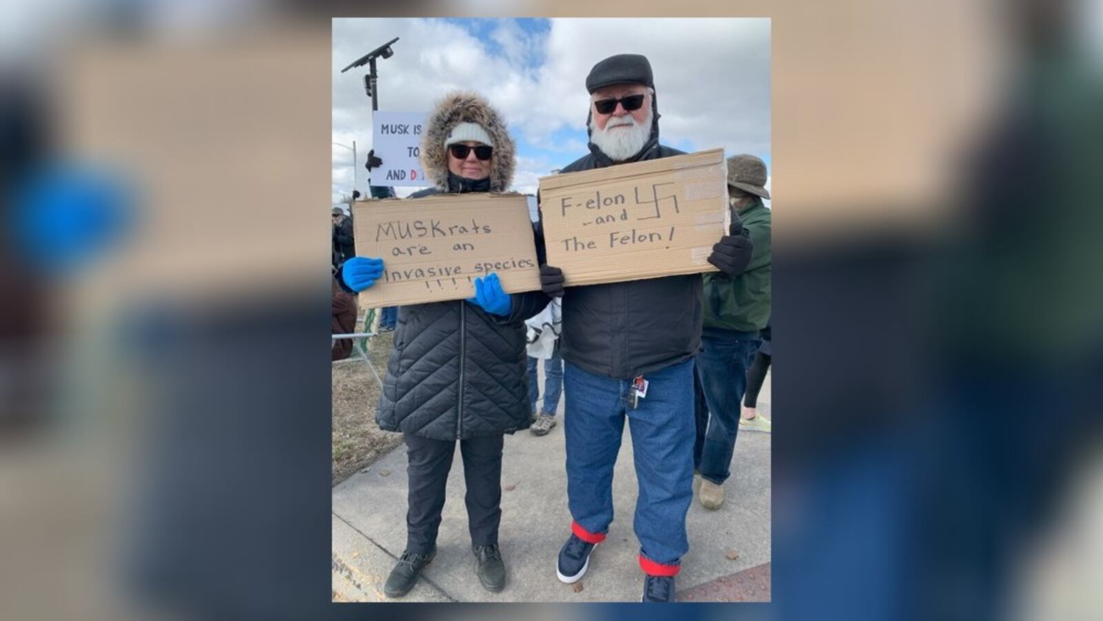 Hundreds of people lined West Dorothy Lane in Moraine on Saturday, March 1, 2025 to protest near a Tesla Service Center, including Carl and Suzanne Geisler (pictured). The protest was aimed at Elon Musk, the world's richest man, and his actions with the Trump administration and the Department of Government Efficiency. BROOKE SPURLOCK/STAFF