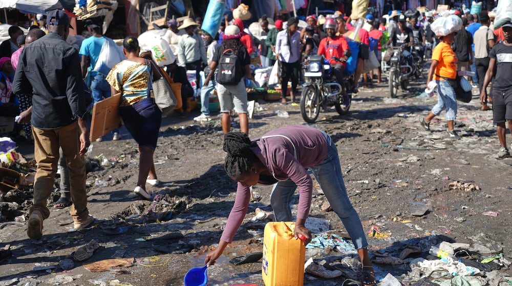 A woman collects water from a puddle in the Petion-Ville neighborhood of Port-au-Prince, Haiti, Wednesday, Feb. 11, 2026. (AP Photo/Odelyn Joseph)