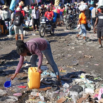 A woman collects water from a puddle in the Petion-Ville neighborhood of Port-au-Prince, Haiti, Wednesday, Feb. 11, 2026. (AP Photo/Odelyn Joseph)