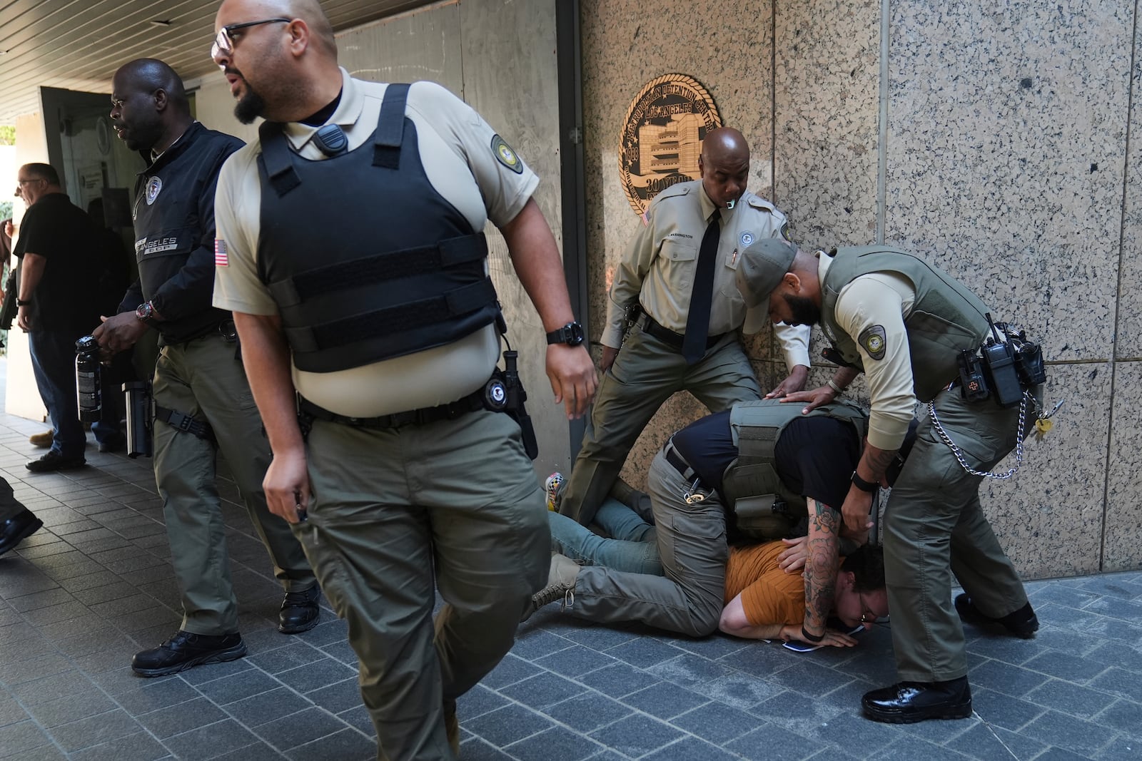 Law enforcement detain a protester at the U.S. Department of Justice Federal Bureau of Prisons after federal immigration authorities conducted an operation on Friday, June 6, 2025, in Los Angeles. (AP Photo/Jae C. Hong)