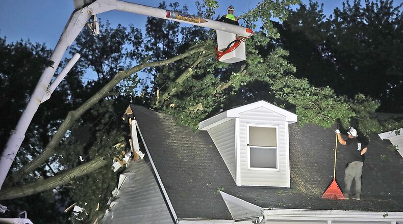 Tree service workers try to remove a large tree that fell on a house Wednesday, June 8, 2022, along Deer Run in German Twp. BILL LACKEY/STAFF