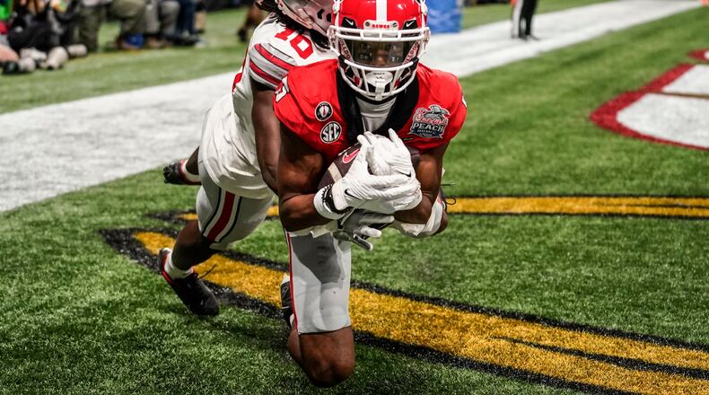 FILE - Then-Georgia wide receiver Adonai Mitchell (5) makes a touchdown catch against Ohio State cornerback Denzel Burke (10) during the second half of the Peach Bowl NCAA college football semifinal playoff game, Saturday, Dec. 31, 2022, in Atlanta. Texas quarterback Quinn Ewers will remain the Longhorns starter, and he has a big new target: Georgia transfer Adonai Mitchell. (AP Photo/Brynn Anderson, File)