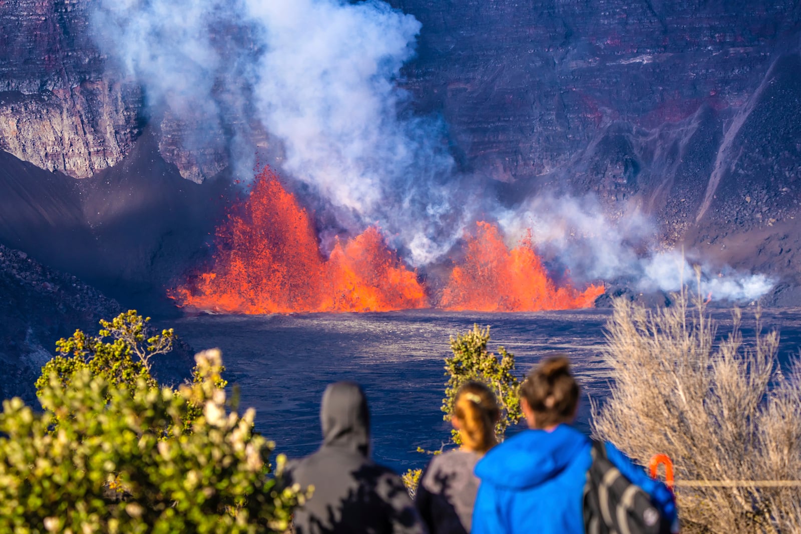 In this photo provided by the National Park Service, people watch as an eruption takes place on the summit of the Kilauea volcano in Hawaii, Monday, Dec. 23, 2024. (Janice Wei/NPS via AP)