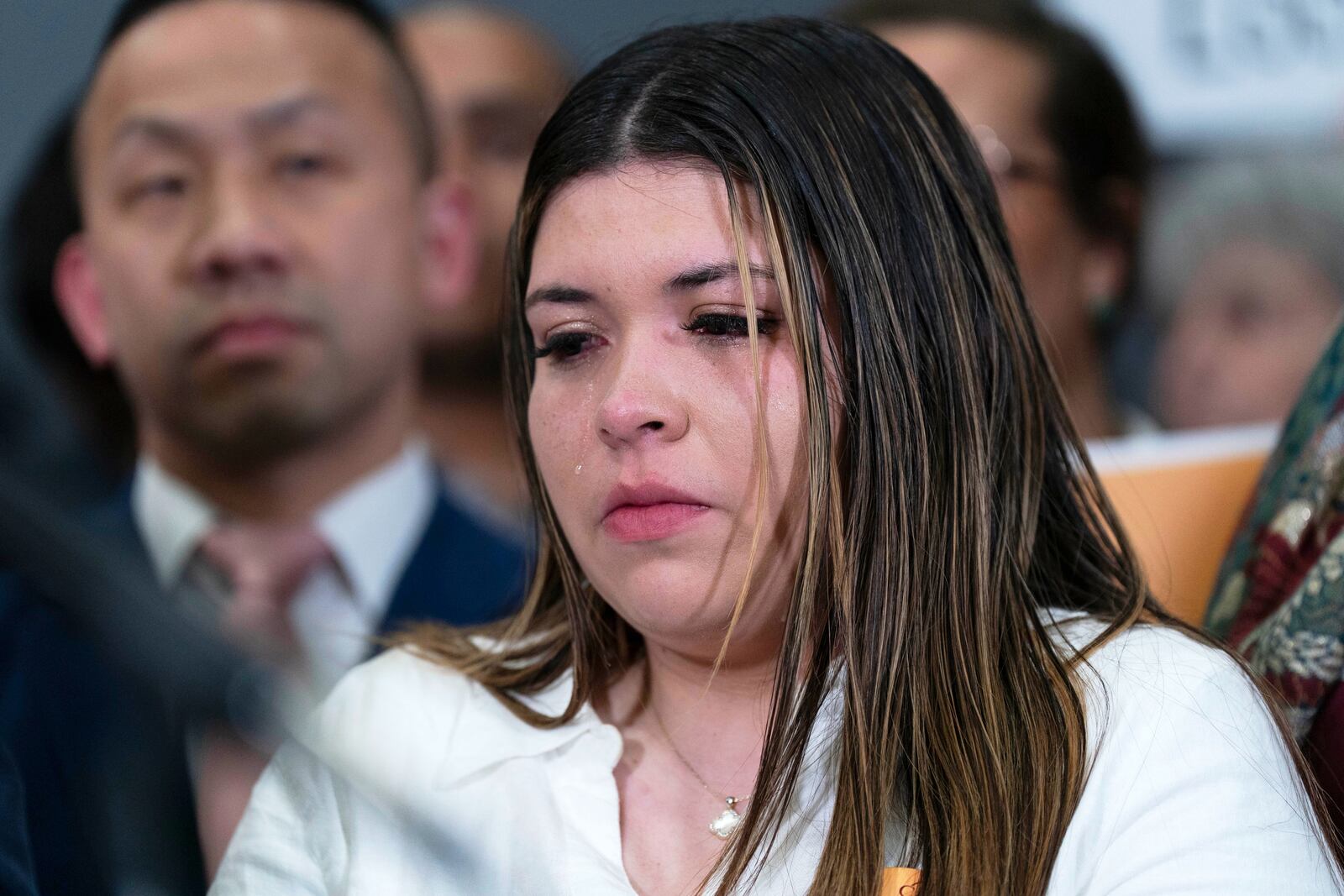 Jennifer Vasquez Sura cries as Sen. Chris Van Hollen, D-Md., speaks during a news conference upon his arrival from meeting with her husband Kilmar Abrego Garcia in El Salvador, at Washington Dulles International Airport, in Chantilly, Va., Friday, April 18, 2025. (AP Photo/Jose Luis Magana)