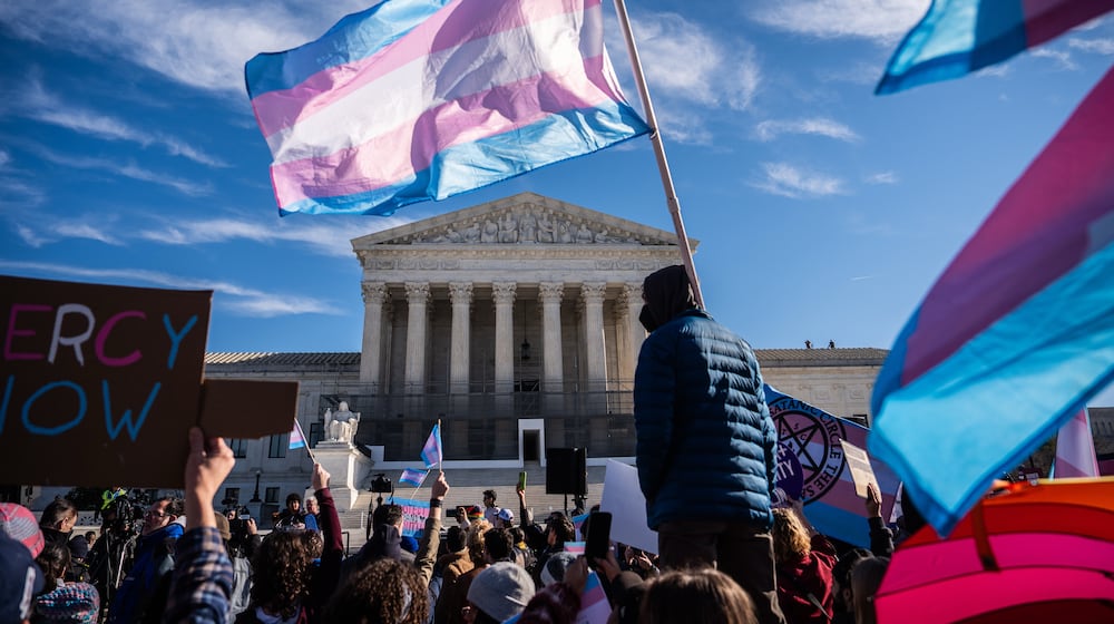 Protesters wave transgender pride flags outside the Supreme Court as it hears arguments over state laws barring transgender girls and women from playing on school athletic teams, Tuesday, Jan. 13, 2026, in Washington. (AP Photo/Julia Demaree Nikhinson)