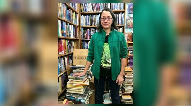Kate Mooneyham, manager of Dark Star Books in Yellow Springs, stands next to a pile of books she plans to give away. SARAH FRANKS/CONTRIBUTED