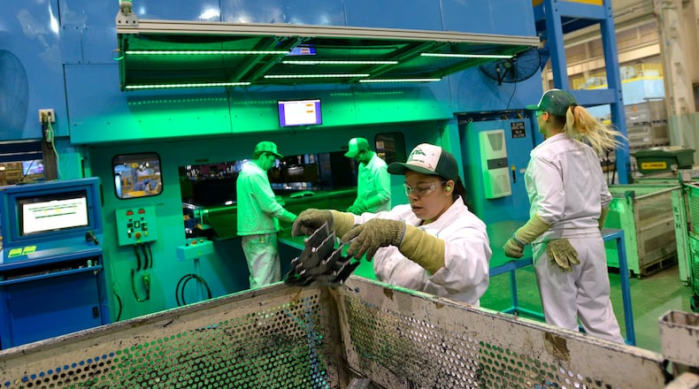 KTH employees inspect the parts as they roll off the new servo press. Bill Lackey/Staff