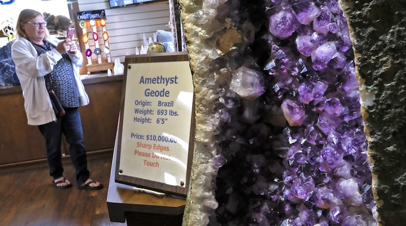 Debbie Thompson, from Pittsburgh, takes a picture of the gen stones on display in the Ohio Caverns gift shop, including the 6’5” Amathyst Geode that was recently brought back from Brazil. Bill Lackey/Staff