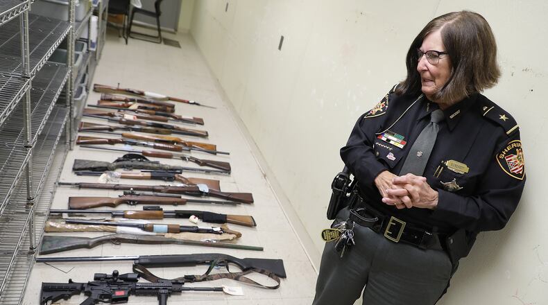 Clark County Sheriff Deb Burchett looks over some of the guns that were removed last week from the evidence room for the Clark County Clerk of Courts. BILL LACKEY/STAFF