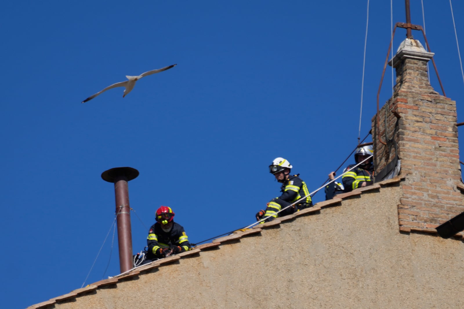 Firefighters place the chimney on the roof of the Sistine Chapel, where cardinals will gather to elect the new pope, at the Vatican, Friday, May 2, 2025. (AP Photo/Gregorio Borgia)