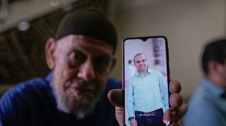 Waleed Husein Ali, shows a picture on a phone of his son, Mohammad, 45, who died in Israeli custody at the Kishon detention center, as he sits in the family's living room in the Nur Shams refugee camp near the West Bank town of Tulkarem, Thursday, Oct. 23, 2025. (AP Photo/Majdi Mohammed)
