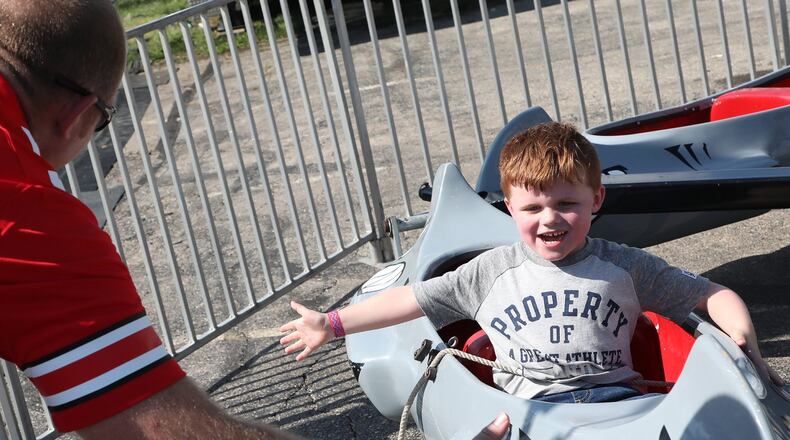 Landon Copeland, 4, smiles as he slaps the hand of his father, Mike, as he passes him on a kiddie ride at the New Carlisle Heritage of Flight Festival Saturday. BILL LACKEY/STAFF