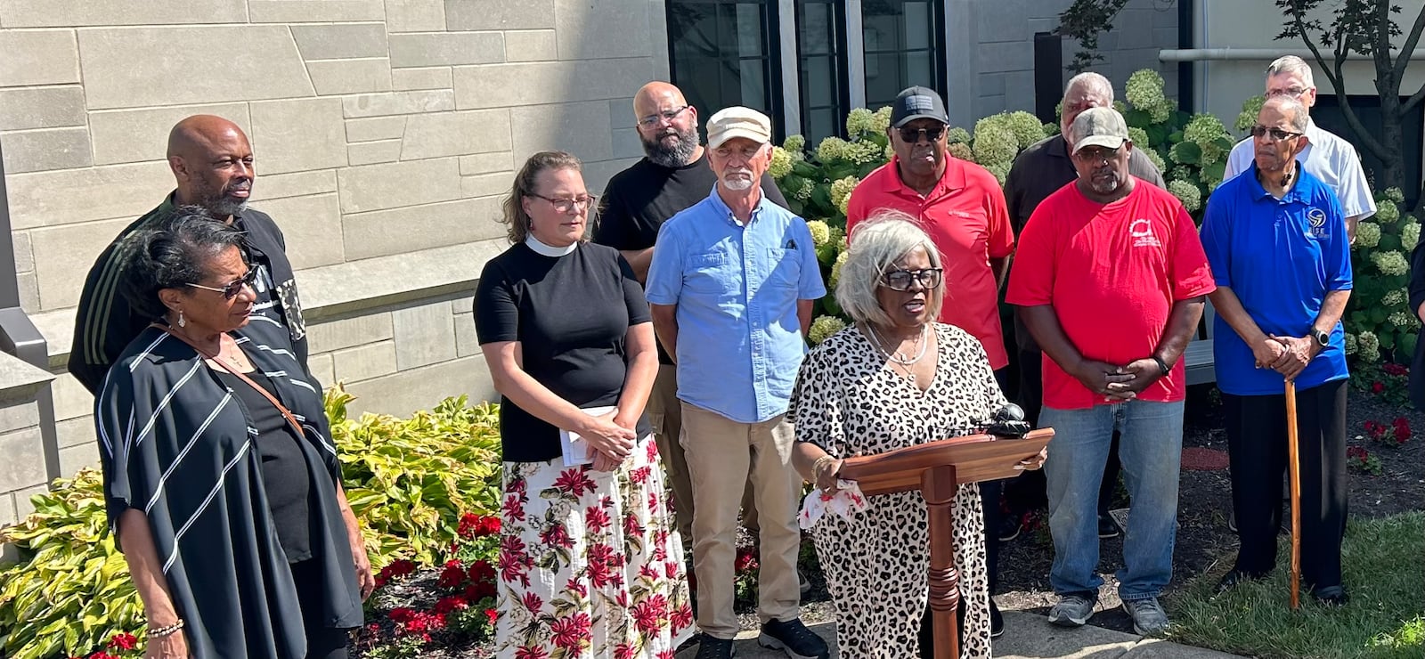 A group of Springfield clergy and community leaders, including Rev. Michelle Boomgaard, third from left, and Denise Williams, at podium, talk about scripture's call to welcome immigrants, at an event Thursday, Sept. 12, 2024. JEREMY P. KELLEY / STAFF