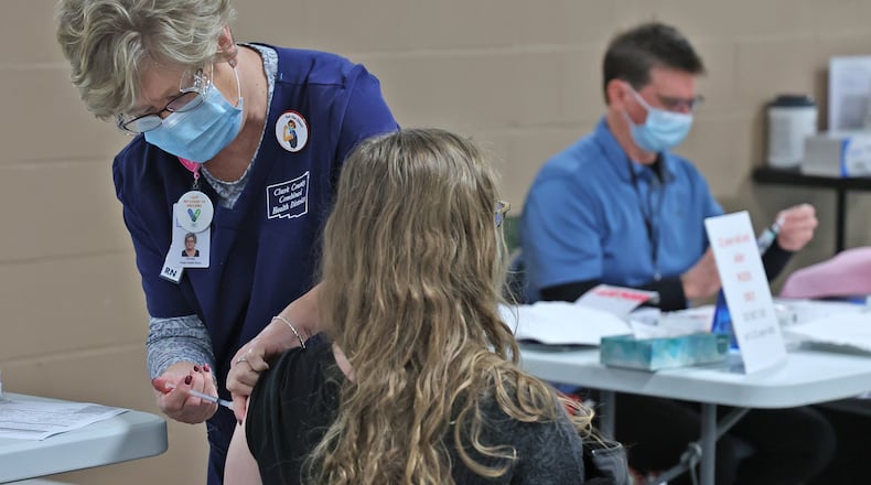 Coronavirus: cases in Clark and Champaign County schools increased by nearly 100 cases this week. Here, a patient gets her COVID booster shot at the Clark County Combined Health District's Vaccine Center Thursday, Jan. 6, 2022. BILL LACKEY/STAFF