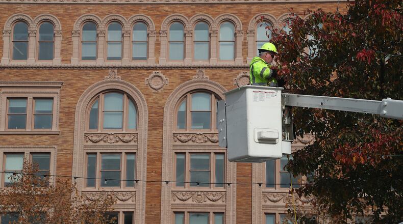 The Bushnell Building provides a back drop as a member of the City of Springfield Service Department decorates one of the trees on the City Hall Plaza Thursday. BILL LACKEY/STAFF