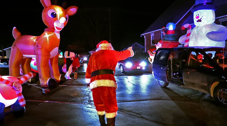 Santa waves to a van full of children Saturday during the New Carlisle Holiday Drive-thru reverse parade in downtown New Carlisle. BILL LACKEY/STAFF