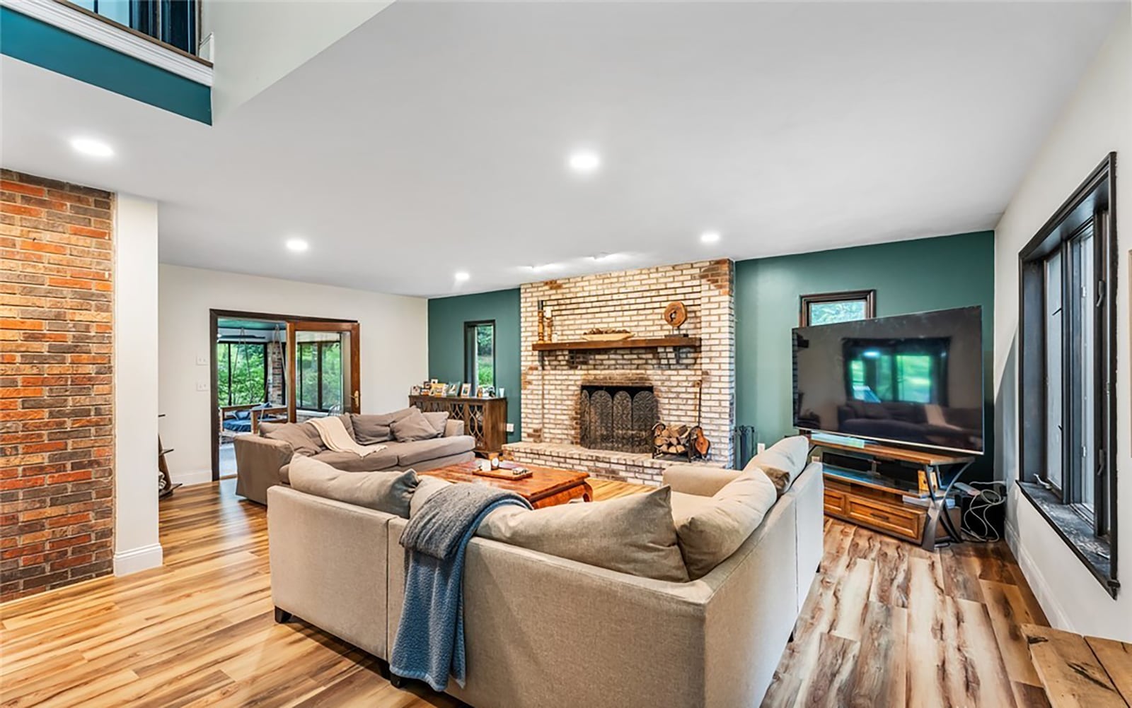 The great room has a stone woodburning fireplace, LVT flooring and an attached three seasons room overlooking the wooded back yard. CONTRIBUTED