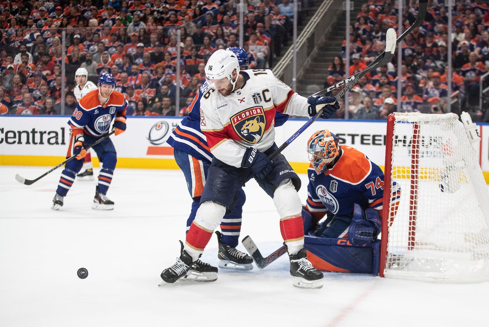 Florida Panthers' Aleksander Barkov (16) and Edmonton Oilers' Evan Bouchard (2) battle in front as goalie Stuart Skinner (74) makes the save during the third period in Game 1 of the NHL hockey Stanley Cup final series in Edmonton, Alberta, Wednesday, June 4, 2025. (Jason Franson/The Canadian Press via AP)