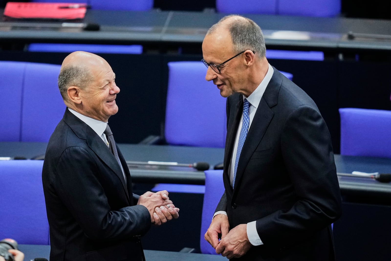 Friedrich Merz, right, talks to outgoing Chancellor Olaf Scholz in the parliament Bundestag in Berlin, Tuesday, May 6, 2025. (AP Photo/Ebrahim Noroozi)