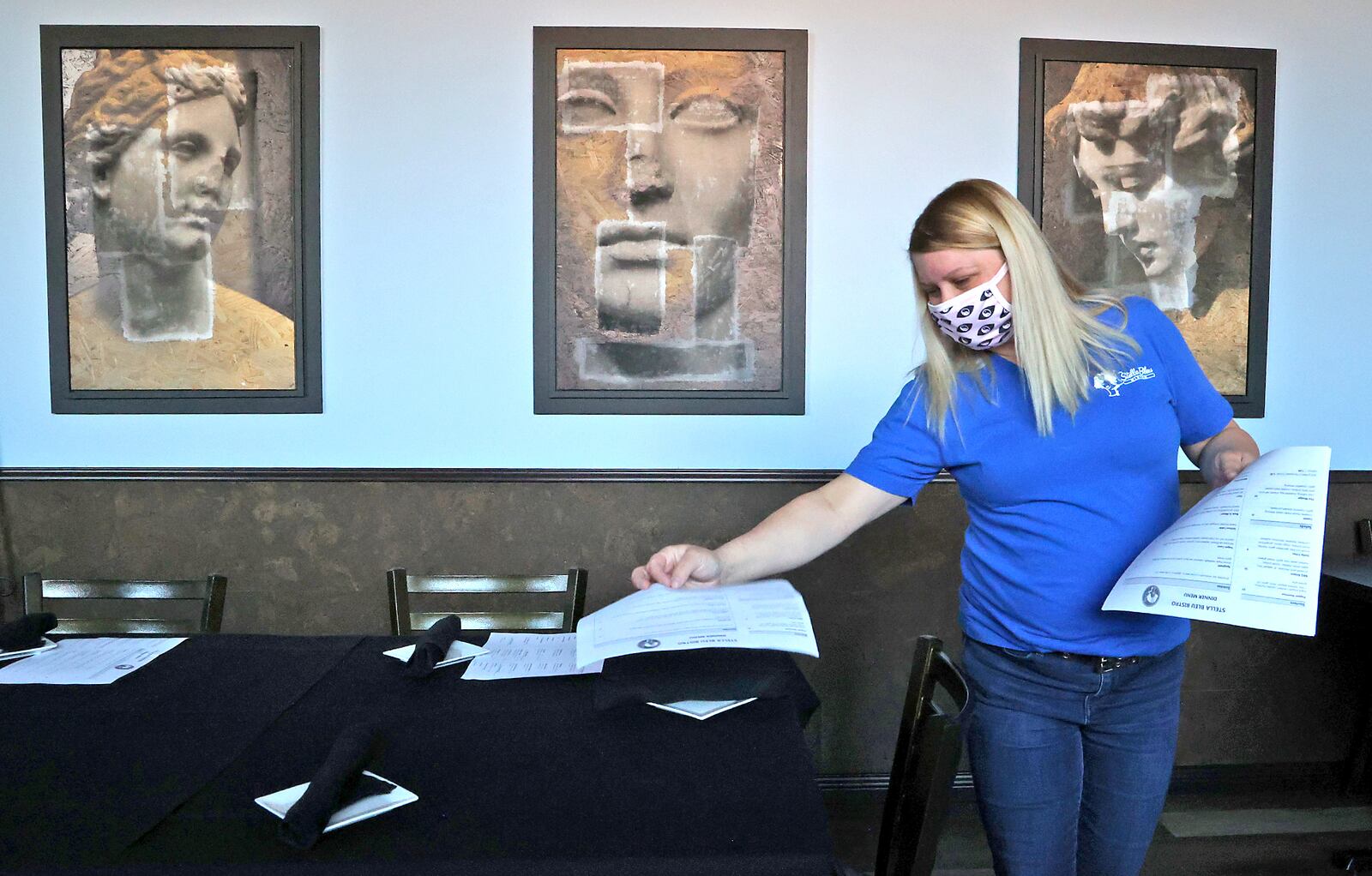 Rhiannon Fraley, an employee at Stella Bleu Bistro sets out menus before the dinner crowd shows up Tuesday. BILL LACKEY/STAFF