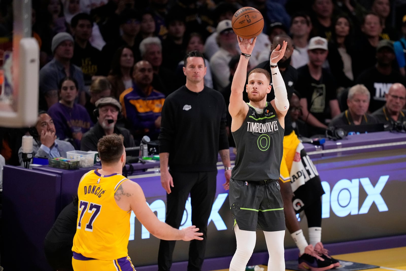 Minnesota Timberwolves guard Donte DiVincenzo (0) shoots over Los Angeles Lakers guard Luka Doncic (77) during the first half in Game 5 of an NBA basketball first-round playoff series Wednesday, April 30, 2025, in Los Angeles. (AP Photo/Mark J. Terrill)