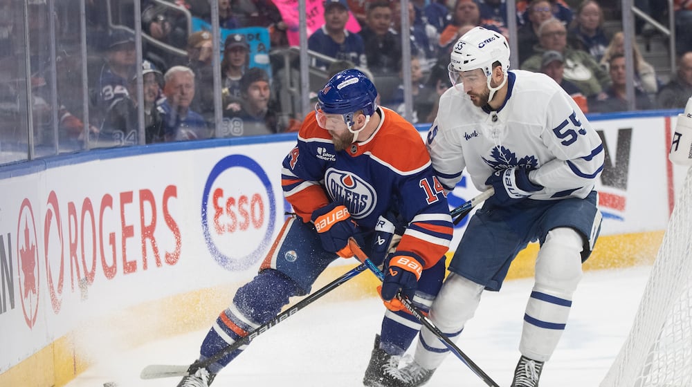 Toronto Maple Leafs' Nicolas Roy (55) and Edmonton Oilers' Mattias Ekholm (14) battle for the puck during first period NHL action, in Edmonton on Tuesday, Feb. 3, 2026. (Jason Franson/The Canadian Press via AP)