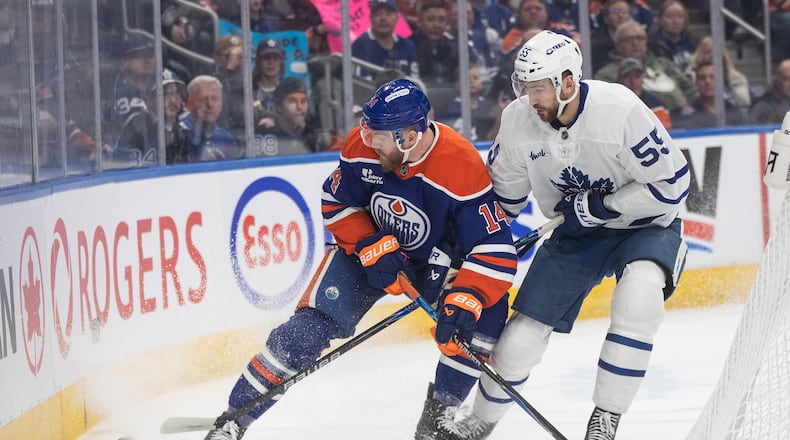 Toronto Maple Leafs' Nicolas Roy (55) and Edmonton Oilers' Mattias Ekholm (14) battle for the puck during first period NHL action, in Edmonton on Tuesday, Feb. 3, 2026. (Jason Franson/The Canadian Press via AP)
