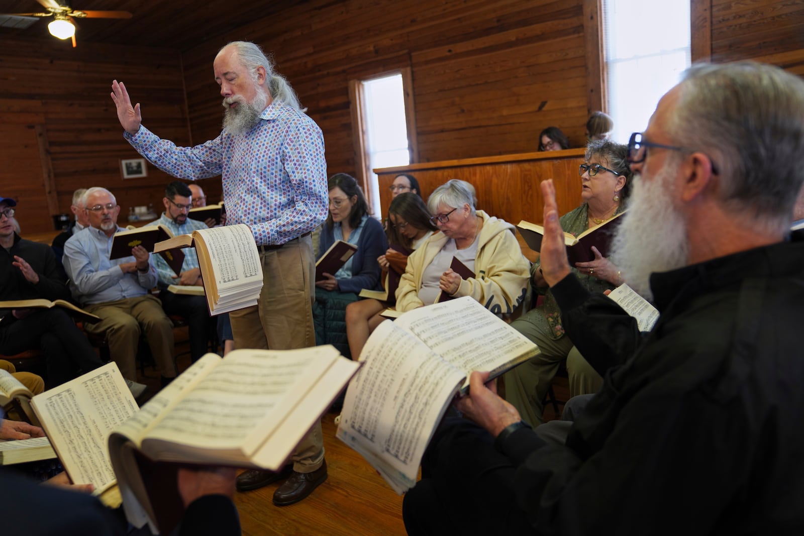 Andy Ditzler stands in the center of a hollow square, "The Sacred Harp" formation in which singers organize into four voice parts and face each other to create an opening in the middle, at Holly Springs Primitive Baptist Church in Bremen, Ga., on Saturday, March 22, 2025. (AP Photo/Jessie Wardarski)